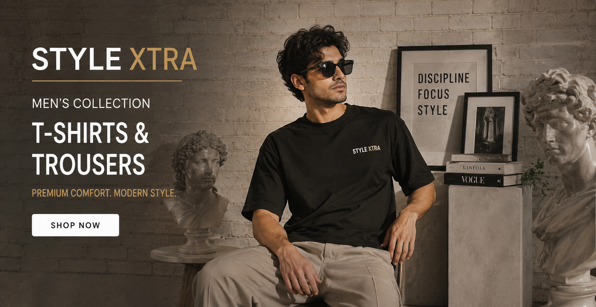 A man wearing a black 'Style Xtra' t-shirt and beige trousers sits in a styled room with a brick wall background, framed prints, and classical busts. Text on the left reads 'STYLE XTRA MEN'S COLLECTION T-ShIRTS & TROUSERS' with a 'SHOP NOW' button.