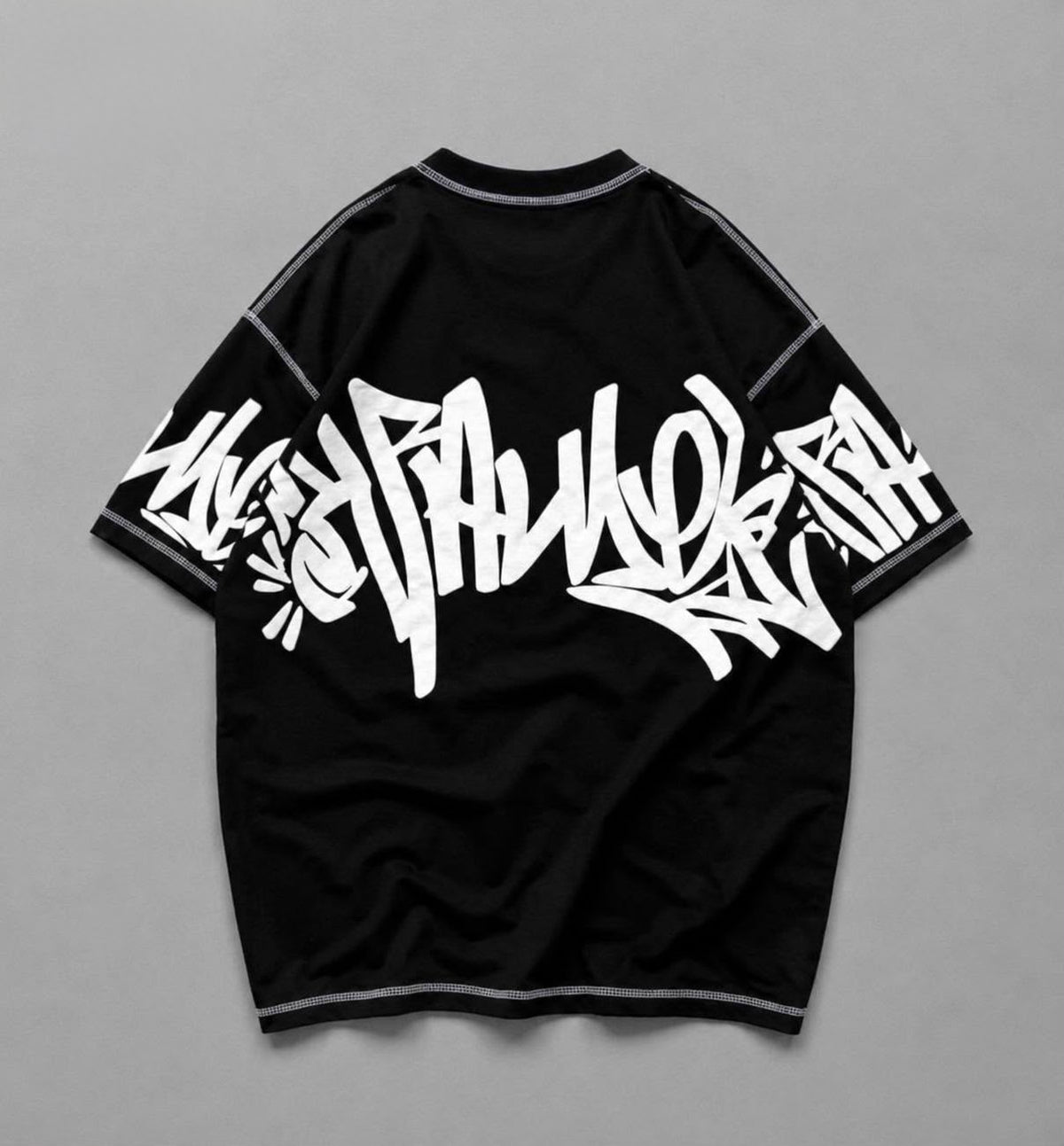 A black short-sleeve t-shirt with a large white graffiti-style graphic printed across the front, displayed flat against a neutral gray background.